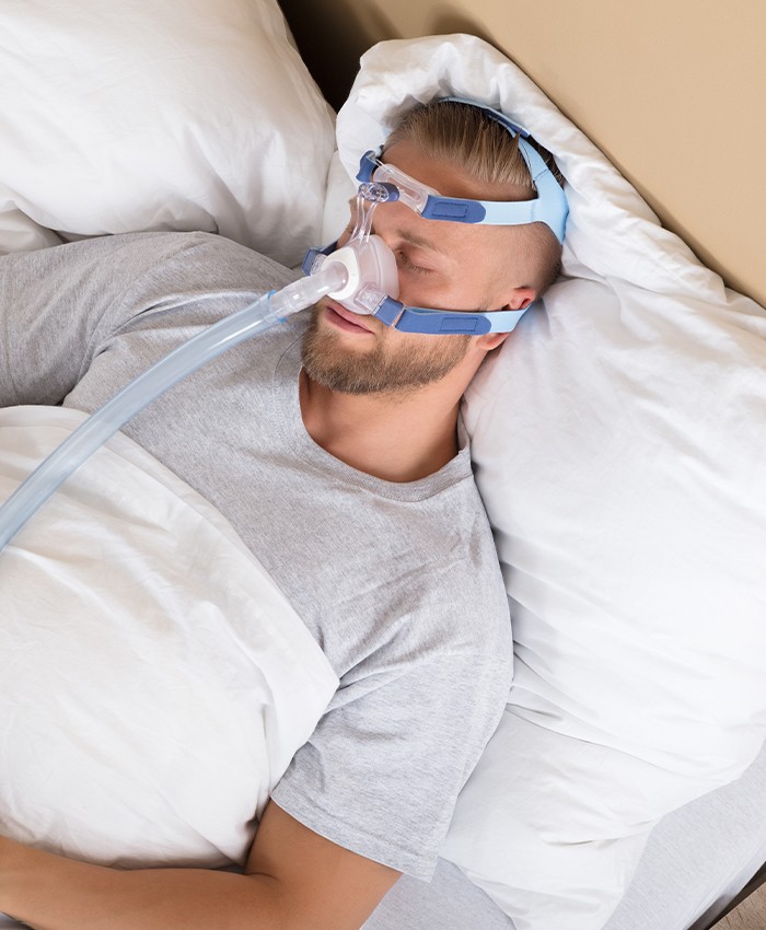Man with C PAP sleep apnea treatment device sleeping
