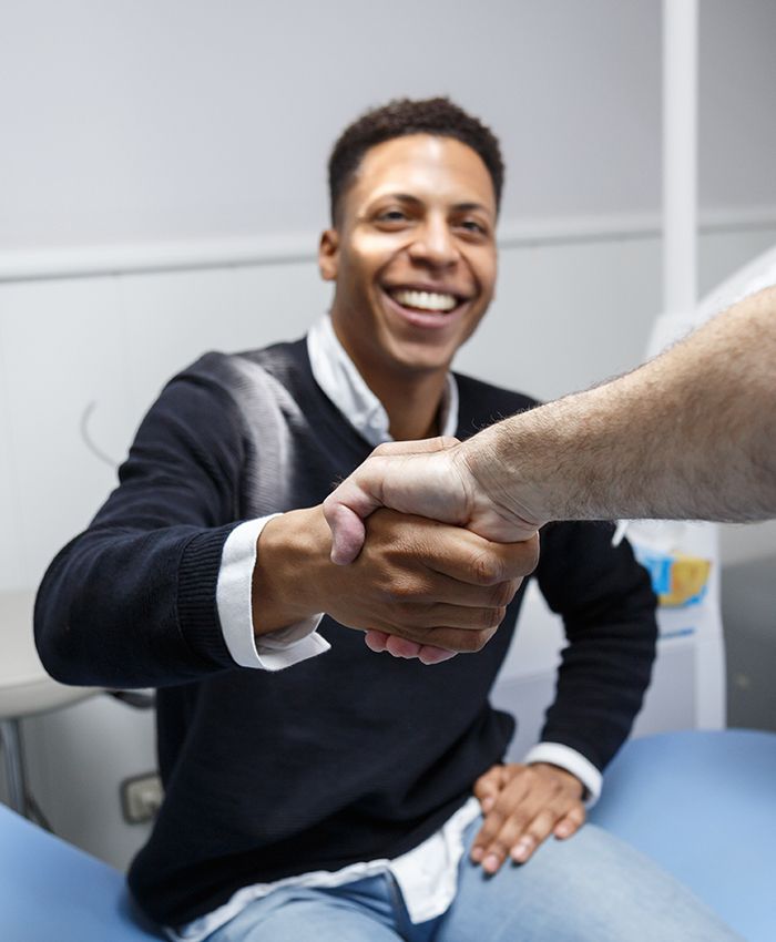 Smiling man shaking hands with his sleep apnea dentist