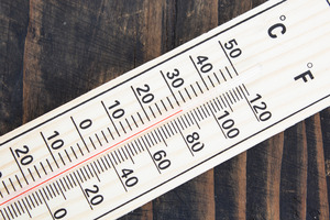 Celsius and Fahrenheit thermometer on wooden surface